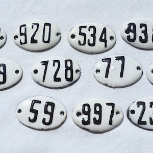 May include: Twelve white oval-shaped porcelain tags with black numbers. The numbers are 152, 920, 534, 938, 25, 19, 728, 77, 903, 59, 997, and 232.