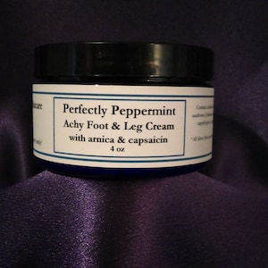 Puede incluir: Un tarro azul y negro de Perfectly Peppermint Achy Foot & Leg Cream con árnica y capsaicina, 4 oz.