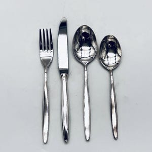 May include: A set of four polished silver cutlery items: a fork, a knife, and two spoons. The silverware has a simple, elegant design with long, slender handles. The fork has four tines, and the knife has a rounded tip.