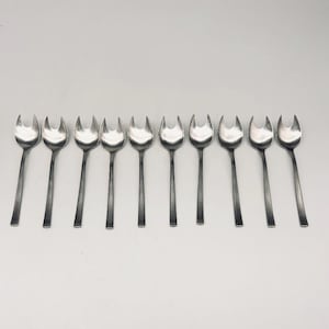 Peut inclure: Un ensemble de dix fourchettes de service argentées, chacune avec une tête à trois dents et un long manche fin. Les fourchettes sont disposées en rangée sur un fond blanc, idéales pour servir des entrées ou des desserts.