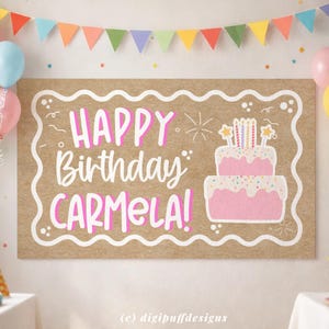 Peut inclure: Une grande bannière d'anniversaire rectangulaire avec les mots "HAPPY Birthday CARMELA!" en lettres roses. Un gâteau rose à deux étages avec des bougies et des étoiles est à droite. La bannière est décorée d'une bordure blanche et de fanions colorés.