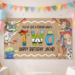 May include: A birthday banner featuring characters from a popular animated movie. The banner says "You've got a friend who's TWO Happy Birthday Jacob!" with colorful illustrations of the characters and a festive banner of triangular flags.