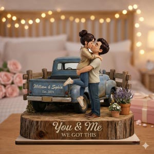 May include: A figurine of a couple kissing, standing in front of a blue pickup truck. The truck bed has the names "William & Sophia Est. 2024". The base reads "You & Me We Got This". The figurine is on a wooden base.