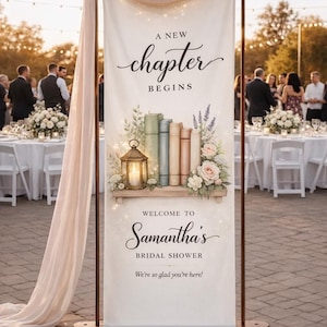May include: A large banner with the text "A New Chapter Begins" and "Welcome to Samantha's Bridal Shower." The banner features a shelf with books, flowers, and a lantern. The banner is set up at an outdoor event.