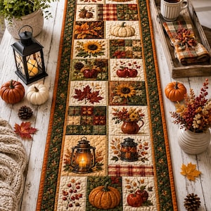May include: A rectangular quilted table runner featuring a patchwork design of autumn-themed squares, including pumpkins, sunflowers, maple leaves, berries, and lanterns in shades of orange, brown, green, and cream with a dark green border.