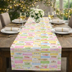 May include: A colorful table runner with a patchwork design featuring floral and bird motifs in pastel colors. The runner is rectangular and placed on a wooden table set for a meal, with plates, silverware, and wine glasses.
