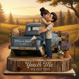 May include: A wedding cake topper featuring a couple kissing in front of a blue vintage truck. The truck bed has the names "William & Sophia" and the year "Est. 2024". The base reads "You & Me We Got This".