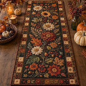 May include: A rectangular quilted table runner featuring a dark green background with an intricate pattern of autumn-themed flowers, including sunflowers and dahlias, surrounded by fall leaves, berries, and acorns, with a checkered border.
