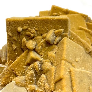 May include: Close-up of a mineral specimen featuring a cluster of cubic and pyramidal formations. The crystals have a warm, golden-brown hue with a textured, granular surface. Small, lighter-colored crystals are scattered throughout the structure.