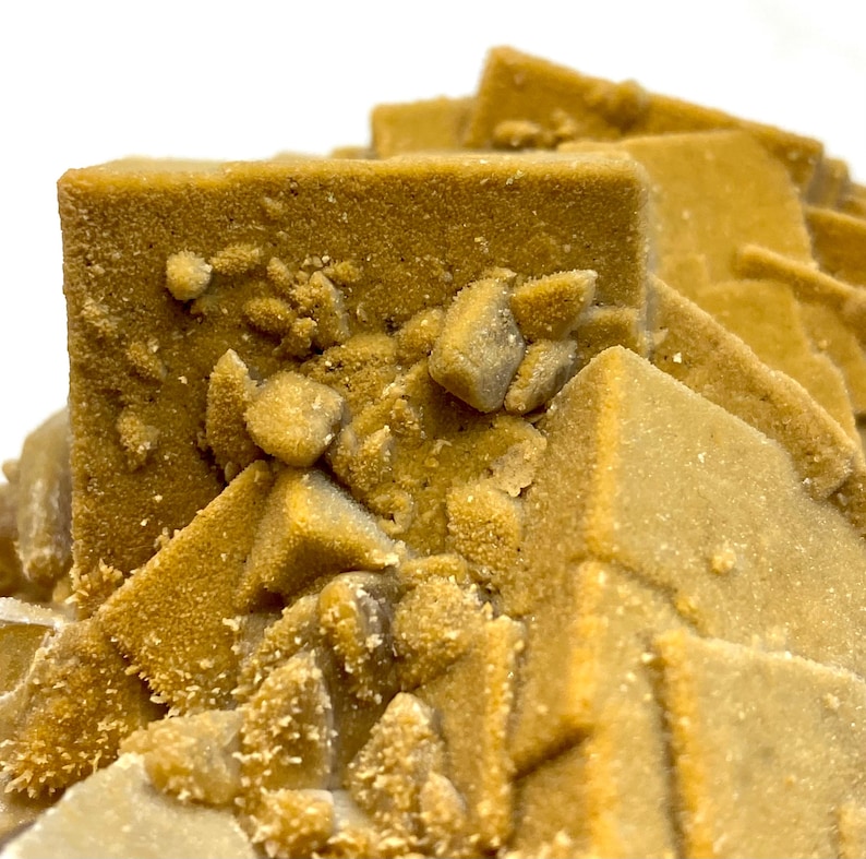 May include: Close-up of a mineral specimen featuring a cluster of cubic and pyramidal formations. The crystals have a warm, golden-brown hue with a textured, granular surface. Small, lighter-colored crystals are scattered throughout the structure.