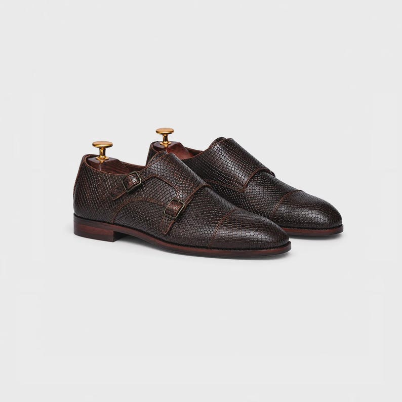 Handmade brown double monk strap shoes for men featuring snake embossed leather texture, cap toe design, dual buckle closure, leather lining and sole, luxury formal footwear ideal for weddings, business attire, office wear, and special occasions.