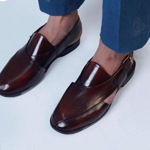 May include: Dark brown leather sandals with a polished finish. The sandals feature a closed-toe design, a strap across the top, and a buckle fastening. The shoes are a deep brown colour.