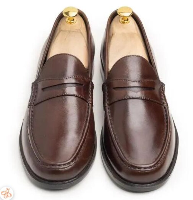 Handmade brown leather penny loafers for men with classic slip-on design, moc toe stitching, and durable rubber sole.