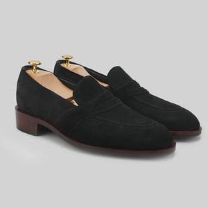 Handmade black suede penny loafers for men featuring a classic slip on silhouette, premium suede leather upper, leather sole, elegant formal design, luxury dress footwear ideal for weddings, business attire, office wear, and special occasions.