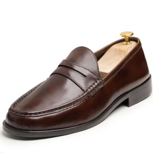 Handmade brown leather penny loafers for men with classic slip-on design, moc toe stitching, and durable rubber sole.