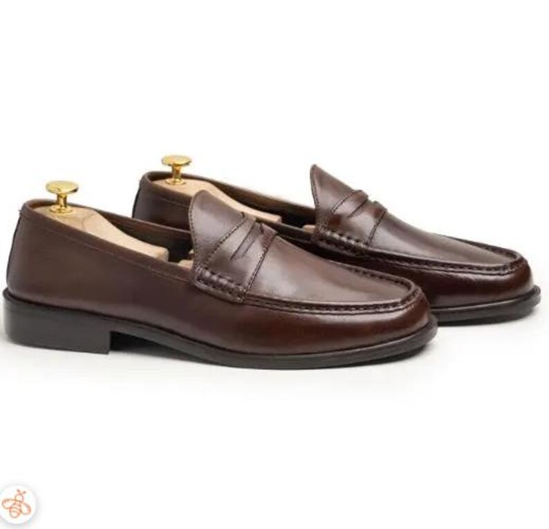 Handmade brown leather penny loafers for men with classic slip-on design, moc toe stitching, and durable rubber sole.