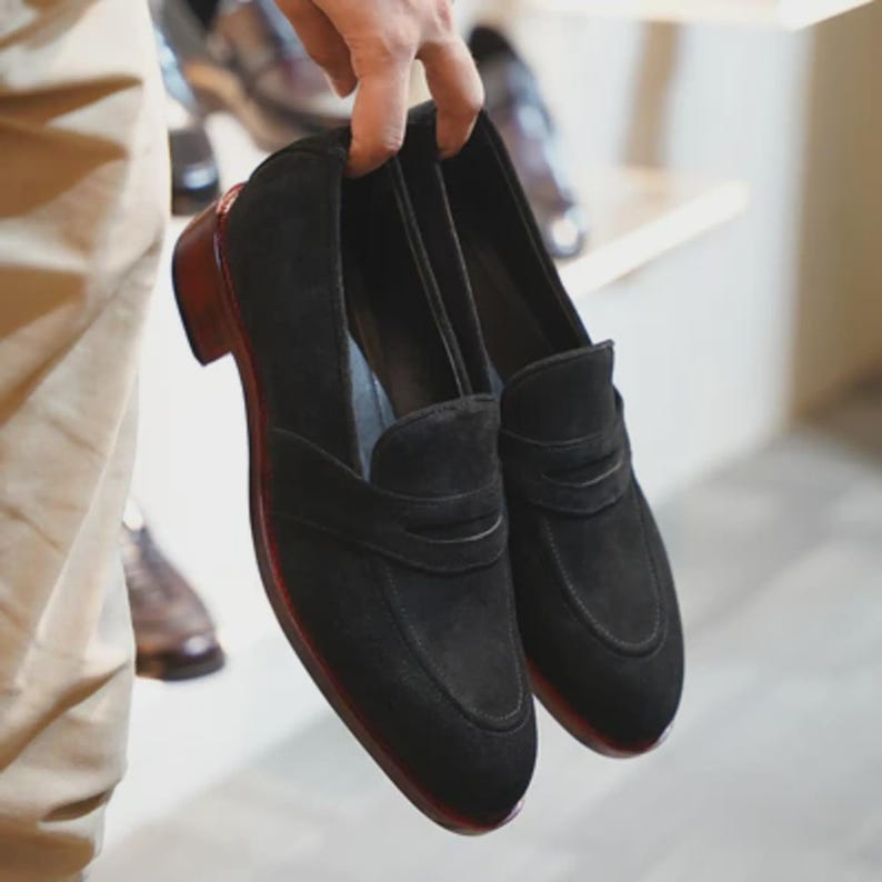 Handmade black suede penny loafers for men featuring a classic slip on silhouette, premium suede leather upper, leather sole, elegant formal design, luxury dress footwear ideal for weddings, business attire, office wear, and special occasions.