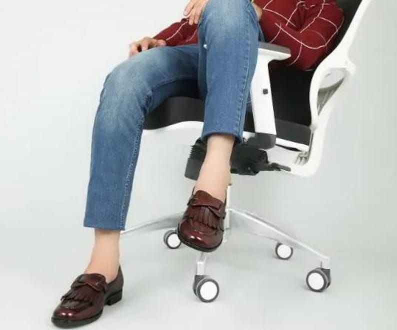 May include: A pair of brown leather loafers with fringe detailing. The loafers have a pointed toe and a low heel.