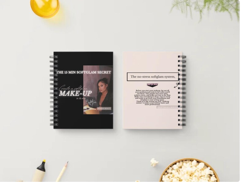 May include: Two spiral-bound notebooks. The black notebook has text that reads "THE 15 MIN SOFTGLAM SECRET" and "Create a softglam MAKE-UP". The other notebook is light pink with the text "The no-stress softglam system."
