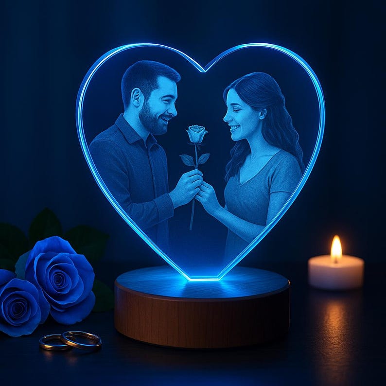 A glowing heart-shaped 3D crystal photo on a wooden LED base, featuring a couple sharing a romantic moment. The engraving shows a man giving a rose to a smiling woman, symbolizing love and affection. Blue LED light enhances the crystal’s details, creating a warm and elegant atmosphere.Roses, wedding rings, and a candle add to the romantic setting, making it perfect for couples.
An ideal personalized gift for anniversaries, weddings, Valentine’s Day, or special celebrations.