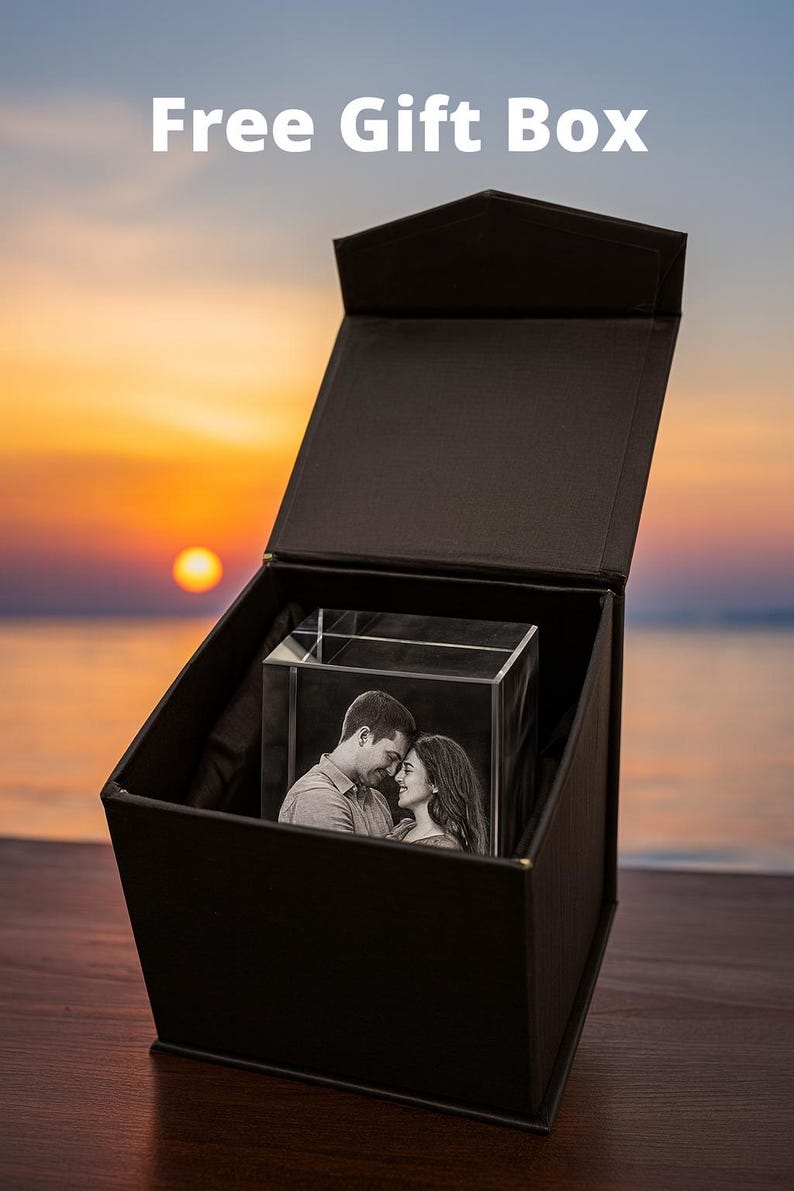 May include: A black gift box opened to reveal a personalized 3D engraved crystal featuring a couple smiling together. A romantic photo etched inside the crystal cube, standing upright inside the elegant gift box. A scenic sunset background with bold white text above the box reading "Free Gift Box".