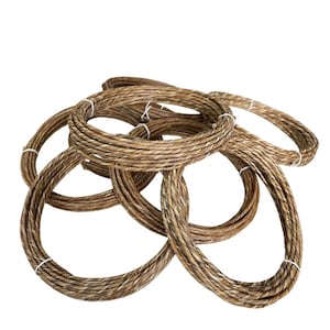 Puede incluir: Varios rollos de cuerda en tonos marrón y beige, atados con hilo blanco. Las cuerdas están dispuestas en bucles superpuestos, creando un patrón circular texturizado. Las cuerdas de fibra natural sugieren un tema rústico o náutico.
