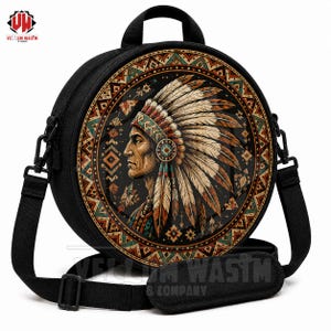 May include: A black circular crossbody bag featuring a central graphic of a person wearing a feathered headdress in profile. The design is surrounded by a geometric border in shades of orange, teal, and brown. It includes a top handle and strap.