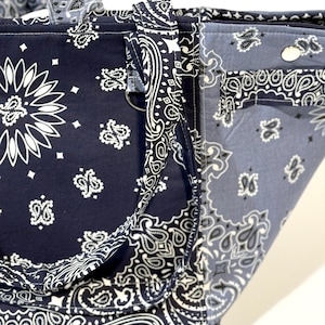 Puede incluir: Un bolso tote con un estampado de pa&ntilde;uelo bandana en azul marino y azul claro. El bolso presenta un dise&ntilde;o de cachemira blanco repetido. Las asas y los ribetes est&aacute;n hechos con la misma tela de pa&ntilde;uelo bandana.