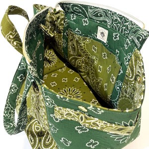 Puede incluir: Bolso tote con estampado de cachemira verde y blanco con cierre de cremallera. La bolsa presenta una variedad de tonos verdes y un interior blanco. La bolsa tiene un asa y varios bolsillos.