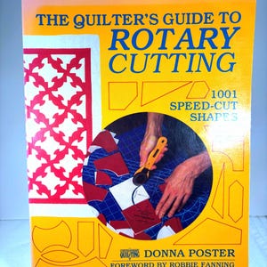 May include: A book titled "The Quilter's Guide to Rotary Cutting" with the text "1001 Speed-Cut Shapes." The cover is yellow and features a red and white quilt design, illustrations, and a photo of hands using a rotary cutter. The author is Donna Poster.