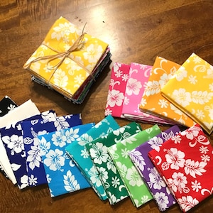 May include: A collection of 12 fabric squares featuring a white hibiscus flower pattern on a variety of coloured backgrounds, including yellow, orange, pink, red, purple, green, blue, and black.