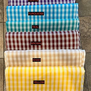 K&ouml;nnte beinhalten: Sechs Stoffrollen in verschiedenen Farben und Mustern. Die Farben sind Lila, T&uuml;rkis, Teal, Braun, Khaki und Gelb. Jede Rolle hat ein wei&szlig;es Etikett mit dem aufgedruckten Farbnamen.