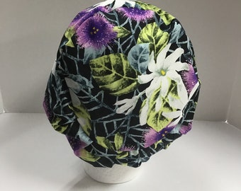 Könnte beinhalten: Eine schwarze OP-Mütze mit einem Blumendruck mit weißen, lila und grünen Blumen auf schwarzem Hintergrund.