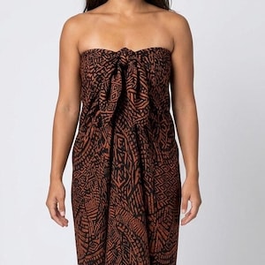 May include: A strapless sarong wrap dress featuring a dark brown and black geometric pattern. The garment is tied at the center of the chest with a knot, creating a draped silhouette that extends downward, covering the torso in a continuous fabric.