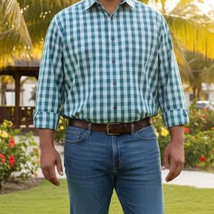 May include: A green and white plaid button-down shirt with rolled-up sleeves, paired with blue jeans and a brown leather belt. The shirt has a classic collar and is buttoned up. The outfit is casual and suitable for everyday wear.