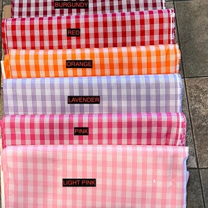 K&ouml;nnte beinhalten: Sechs Stoffrollen in verschiedenen Farben, darunter Burgunder, Rot, Orange, Lavendel, Rosa und Hellrosa. Jede Rolle hat ein wei&szlig;es und farbiges Karomuster.