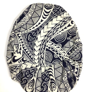 May include: A white and black patterned fabric with a tribal design. The fabric is folded into a rounded shape.