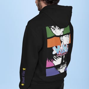 Pode incluir: Camisola de capuz preta com uma estampa gráfica colorida de personagens de anime do programa "Yu Yu Hakusho". A estampa apresenta os personagens Yusuke Urameshi, Kurama, Hiei e Kuwabara. As mangas têm o texto "Ghost Files" impresso nelas.