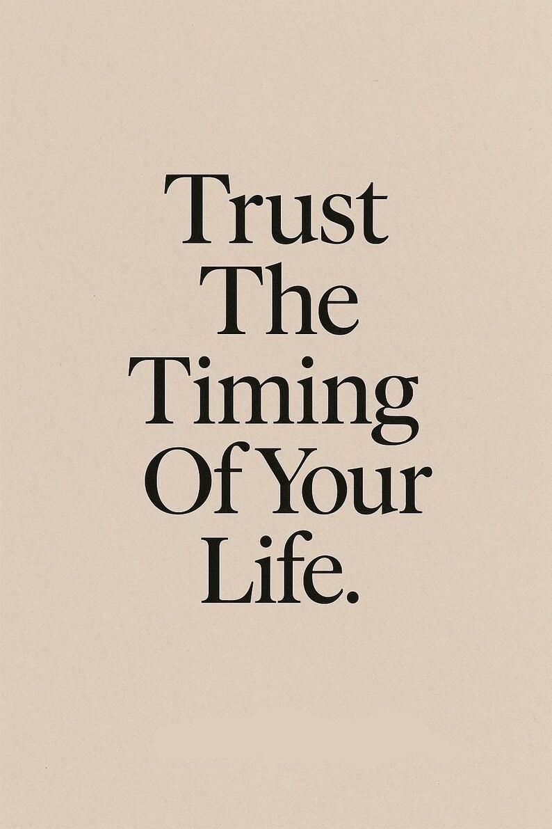 May include: A minimalist print on a beige background with the words "Trust The Timing Of Your Life" in a bold, black serif font. The text is centered, creating a balanced and calming aesthetic.