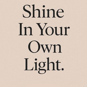 May include: A vertical poster with the text "Shine In Your Own Light" in a bold, black serif font. The text is centered on a light beige background, creating a minimalist and inspirational design.