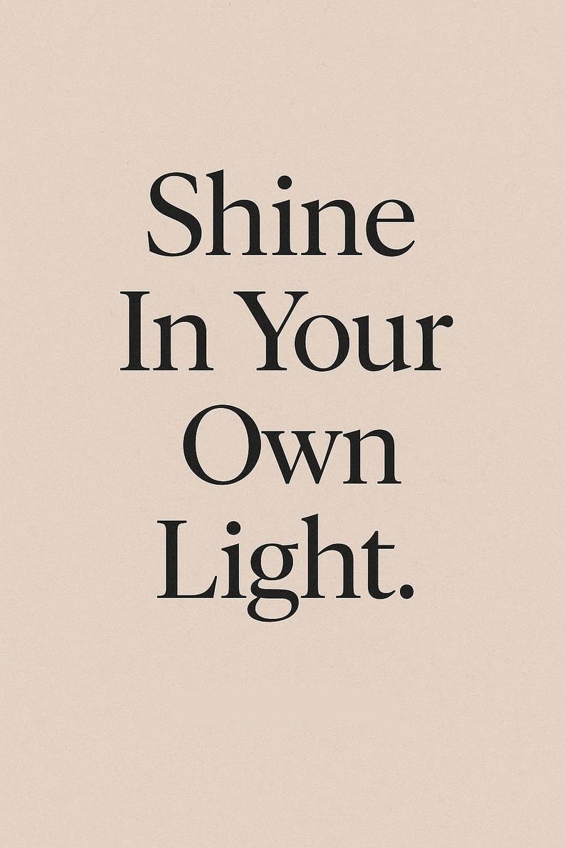 May include: A vertical poster with the text "Shine In Your Own Light" in a bold, black serif font. The text is centered on a light beige background, creating a minimalist and inspirational design.