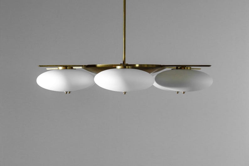 May include: A brass and white glass chandelier with three oval-shaped lights.