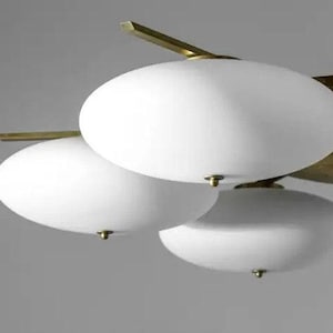 May include: A brass and white glass chandelier with multiple round, white glass shades. The chandelier has a modern design and is suspended from the ceiling.