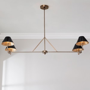 May include: A bronze-toned, multi-light chandelier with four black cone-shaped shades. The interior of each shade is gold. The fixture is suspended from the ceiling with a central rod and a horizontal bar.