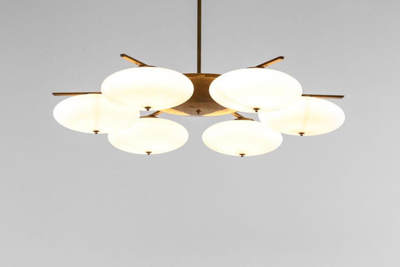 May include: A brass and white glass chandelier with six lights. The chandelier has a starburst design with five arms and six round, white glass shades.