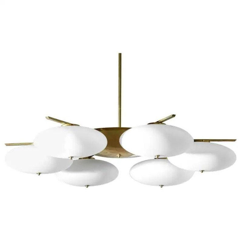 May include: A brass and white glass chandelier with six lights. The chandelier has a circular base with six arms extending out, each with a white glass shade.
