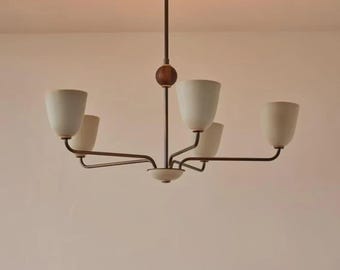 May include: A mid-century modern chandelier with five off-white cone-shaped shades. The fixture has a dark brown central rod with a wooden sphere and brass-colored arms extending to hold the shades. The chandelier is designed for ceiling mounting.