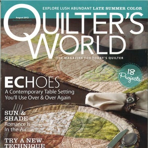 May include: Quilter's World magazine cover featuring a table setting with a round, multi-colored quilted placemat. The placemat has a sun and shade design with shades of green, brown, and white. The text on the cover reads "Echoes: A Contemporary Table Setting You'll Use Over & Over Again".