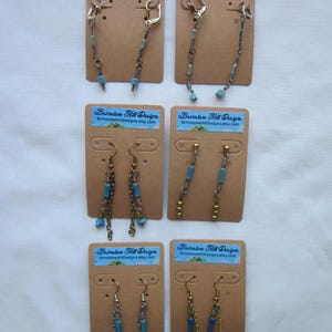 May include: Six pairs of dangle earrings on brown card stock with the text "Brimstone Hill Designs" and the website address "BrimstoneHillDesigns.etsy.com". The earrings are made with silver and gold chains and blue and turquoise beads.