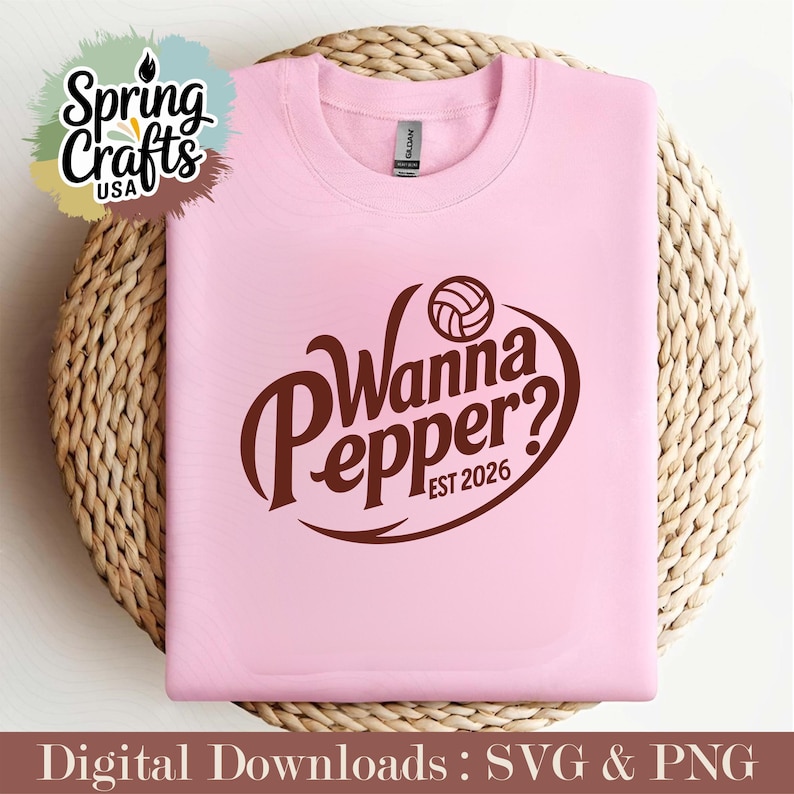 May include: A light pink sweatshirt with the text "Wanna Pepper? EST 2026" in brown. The design includes a volleyball graphic. The sweatshirt is displayed on a woven, circular surface. The words "Spring Crafts USA" are in the upper left corner.
